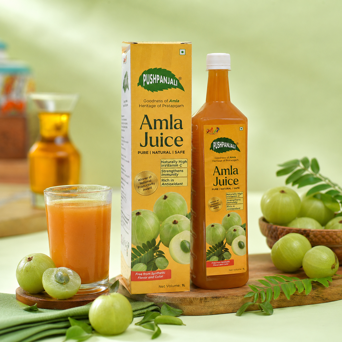 A bottle and box of Pushpanjali Amla Juice are displayed on a wooden board with whole amlas, a glass of amla juice, and green leaves against a soft green background.